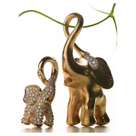 Elevated close-up captures two ornate golden elephant figurines adorned with diamonds, complemented by a gracefully curving green plant stem.