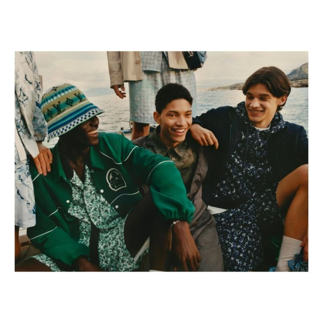 Group of young men wearing casual summer clothing and hats pose outdoors near water for a fashion editorial.