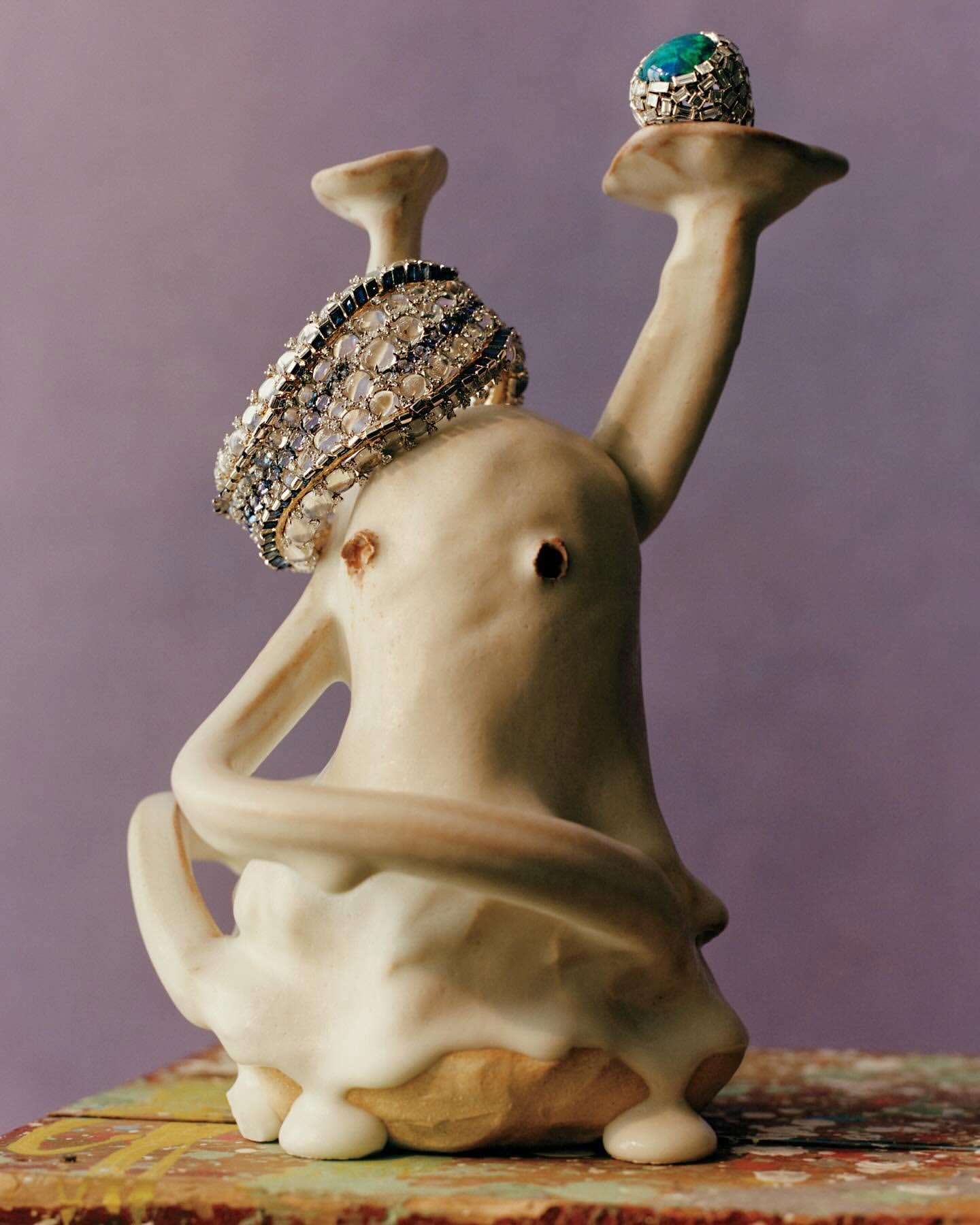 Jewellery display featuring a diamond bracelet and a ring with a turquoise stone, presented on a sculptural ceramic stand against a lilac background.