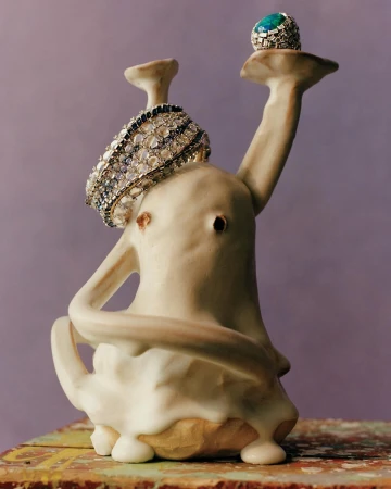 Jewellery display featuring a diamond bracelet and a ring with a turquoise stone, presented on a sculptural ceramic stand against a lilac background.