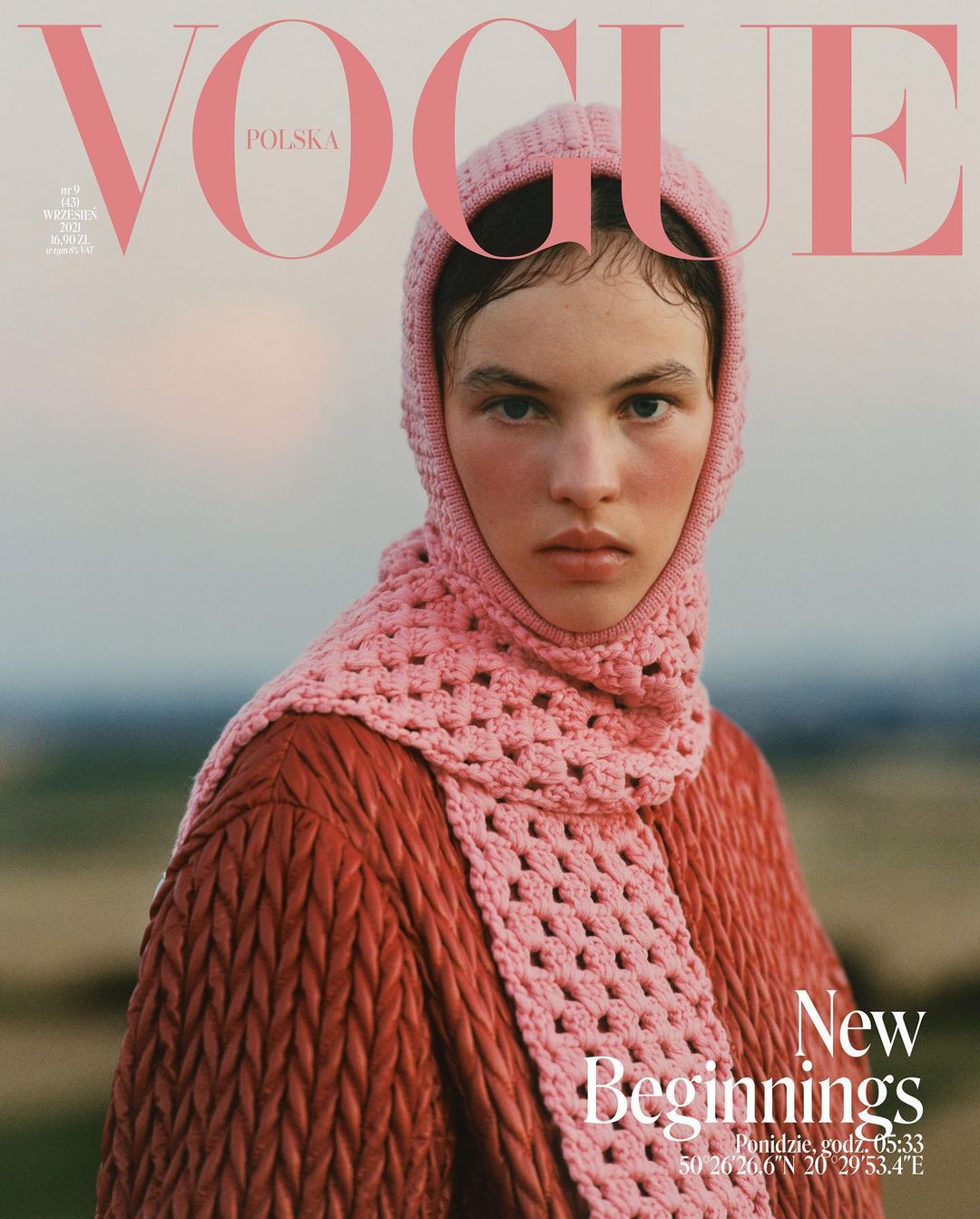 Vogue Polska cover featuring a model with fair skin, wearing a pink crocheted hood, scarf, and textured red-brown jacket against a blurred outdoor backdrop.