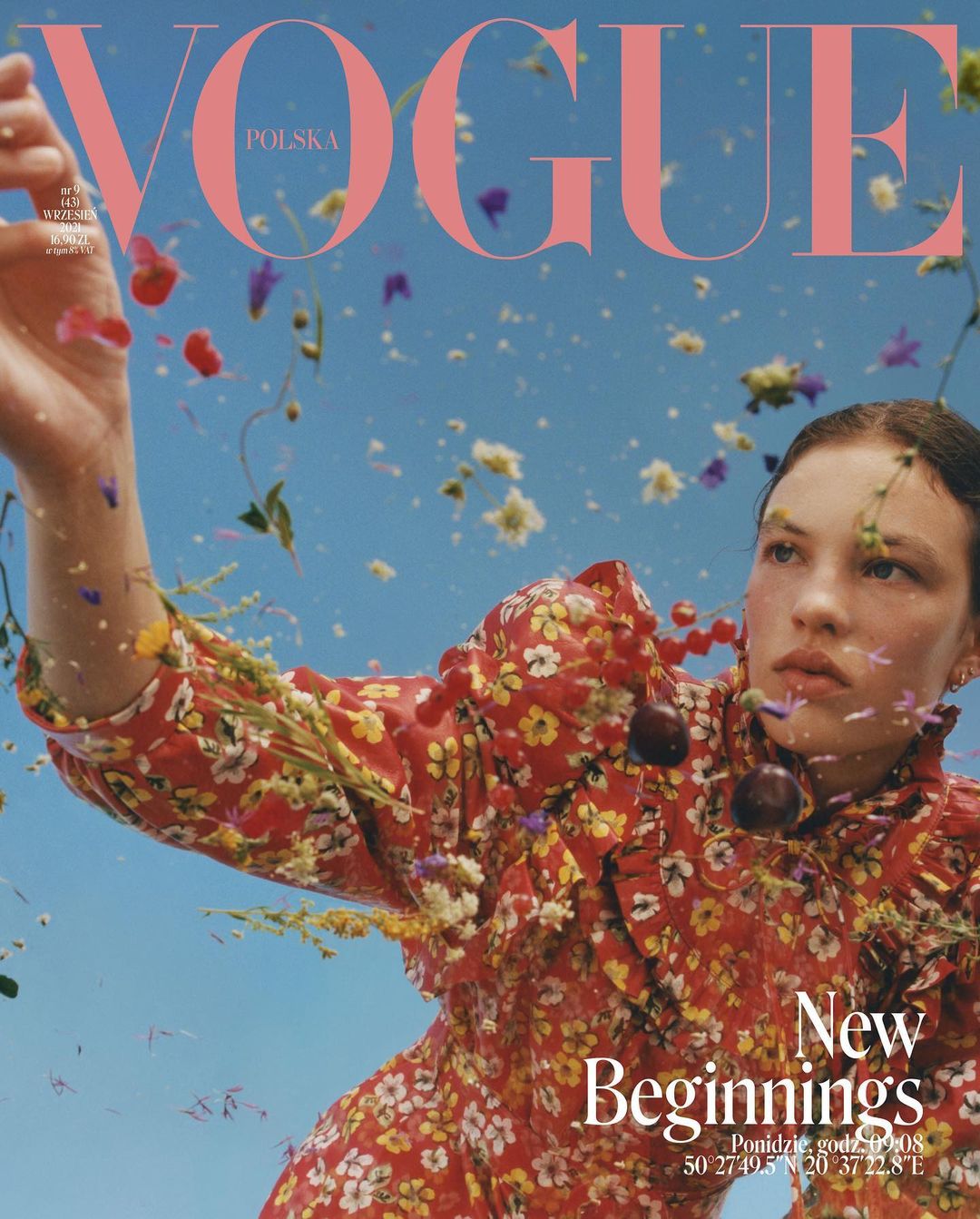 Vogue Polska magazine cover featuring a model in a floral dress, adorned with cherries, against a bright blue sky with flowers.
