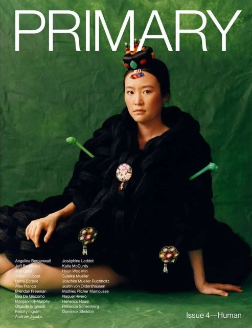 Magazine cover featuring an Asian female model in a decorative black coat and headdress, set against a green backdrop with white text.