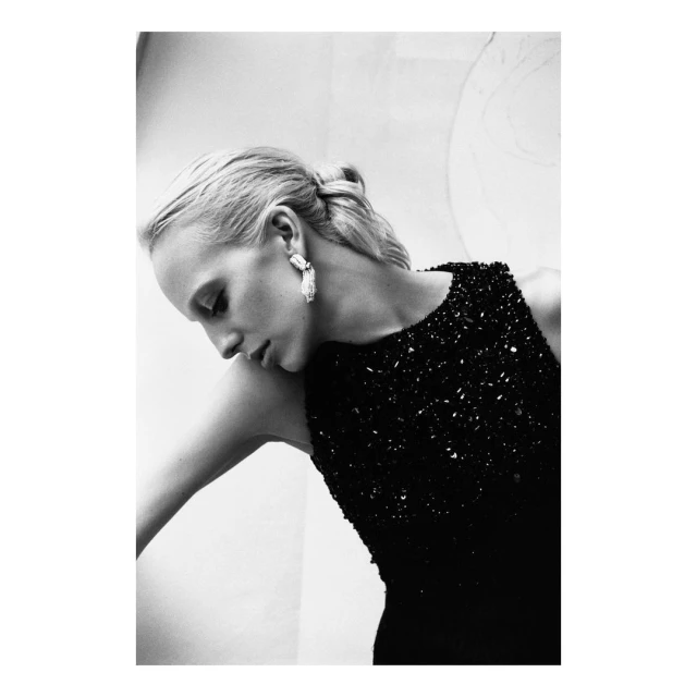 Monochrome portrait of a fair-skinned adult woman wearing a sequined black dress and teardrop earrings, head tilted downwards.