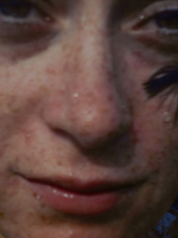 Close-up portrait of a young adult female with freckles, visible make-up and a tear running down her cheek.