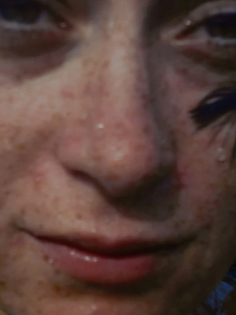 Close-up portrait of a young adult female with freckles, visible make-up and a tear running down her cheek.