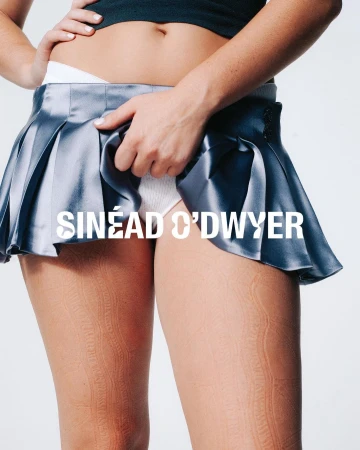 Close-up portrait of a model wearing a grey pleated miniskirt and white underwear photographed by Zoe Natale Mannella.