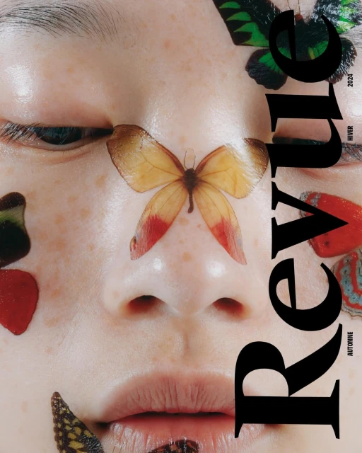 Close-up fashion shot of a fair-skinned person with butterfly decals on their face, next to the masthead for Revue magazine.