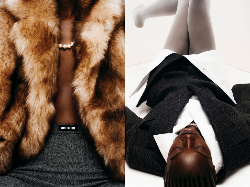 Fashion shot showcases a woman in a fur coat and a second woman in a suit lying on her back, shot in a bright studio.