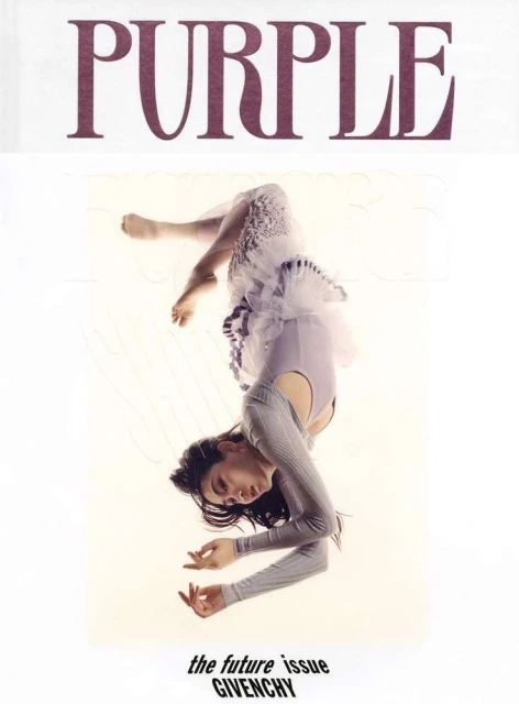 Magazine cover featuring a woman in a light purple dress and grey sweater, upside down against a white background, with bold 'PURPLE' text.