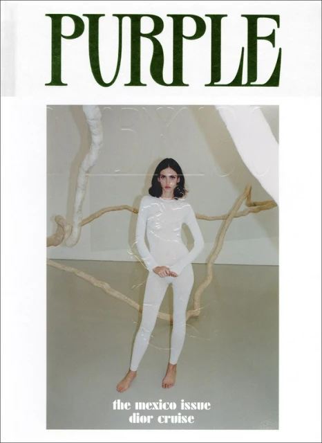 Magazine cover featuring a model in a white bodysuit posing in front of an art installation, with 'PURPLE' in green text above.