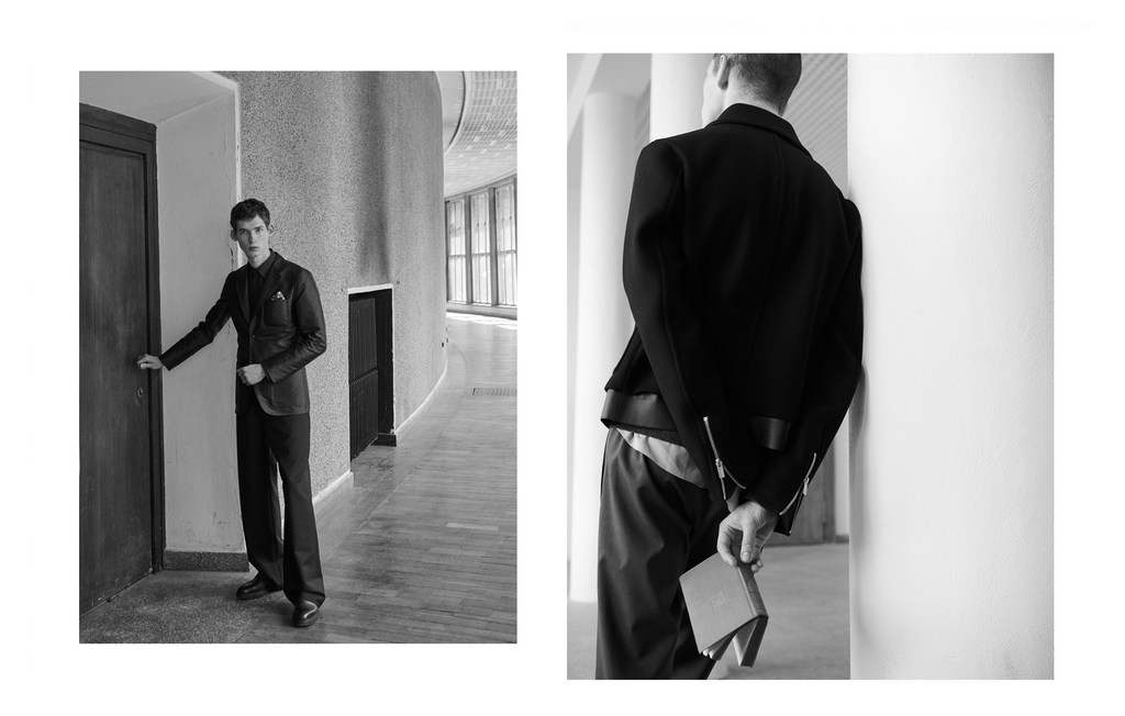 Monochrome fashion shot of a young adult man in a suit by a door, contrasted with a man in a jacket holding a book in a hallway.