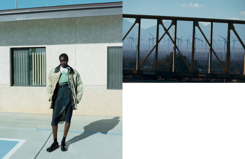 Fashion shot of a woman wearing a jacket and skirt in front of a building, complemented by a blurred background of wind turbines.