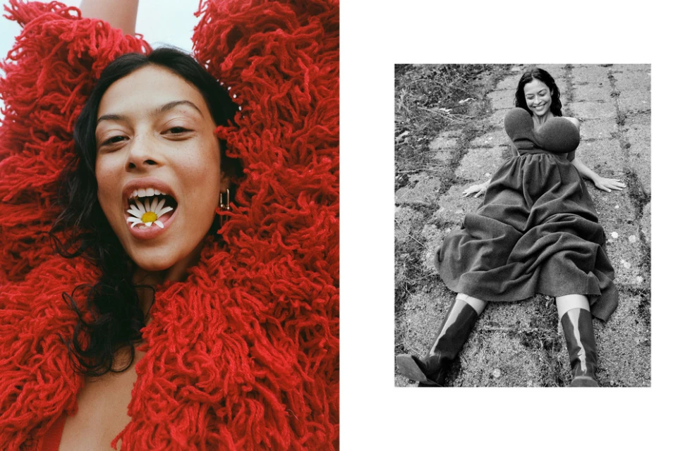 Fashion editorial with a young woman in a shaggy red jacket and another woman in a dress lying on a stone surface in a black and white shot.