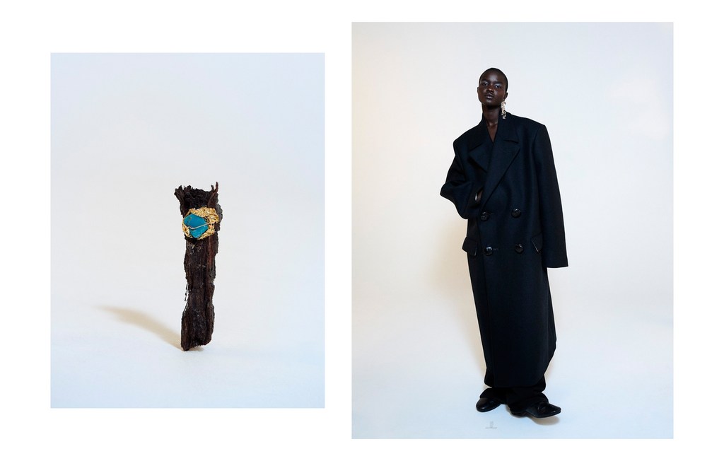 Studio shot features a Black woman wearing a long black coat against a white backdrop, alongside an ornate stick.