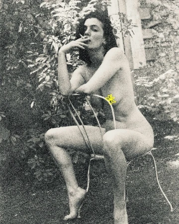 Monochrome portrait of a nude woman smoking, sitting on a metal chair outdoors with foliage in the background, creating a vintage aesthetic.