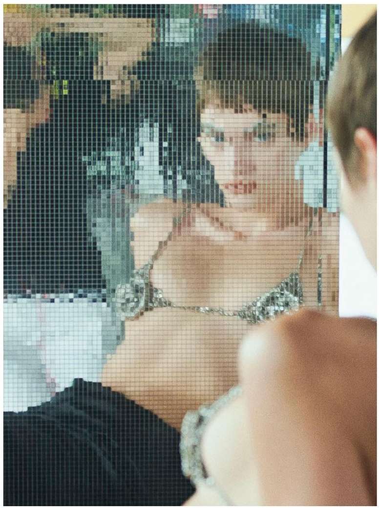 Pixelated image featuring a woman in a silver bra, reflected in a pixelated mirror, creating a digital and artistic effect.