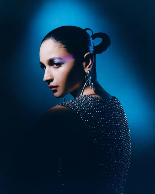 Elegant woman in a studded top poses in a studio. Close-up shot of a woman with creative makeup and sculptural silver earrings.