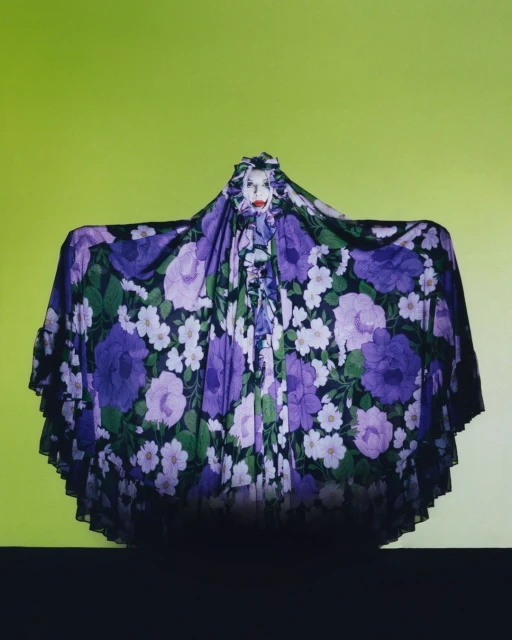 Artistic portrait of a person covered in a floral fabric, with a green background. Fashion and creative expression combine in this surreal image.
