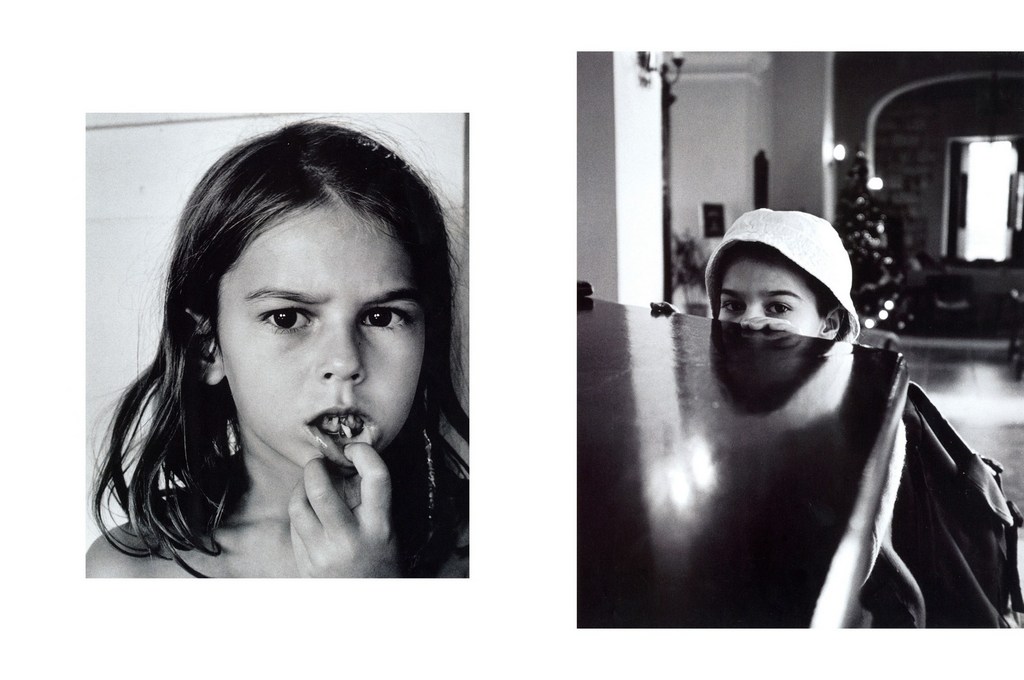Black and white portrait of a child's face with a missing tooth, plus another child partially visible behind a table indoors.