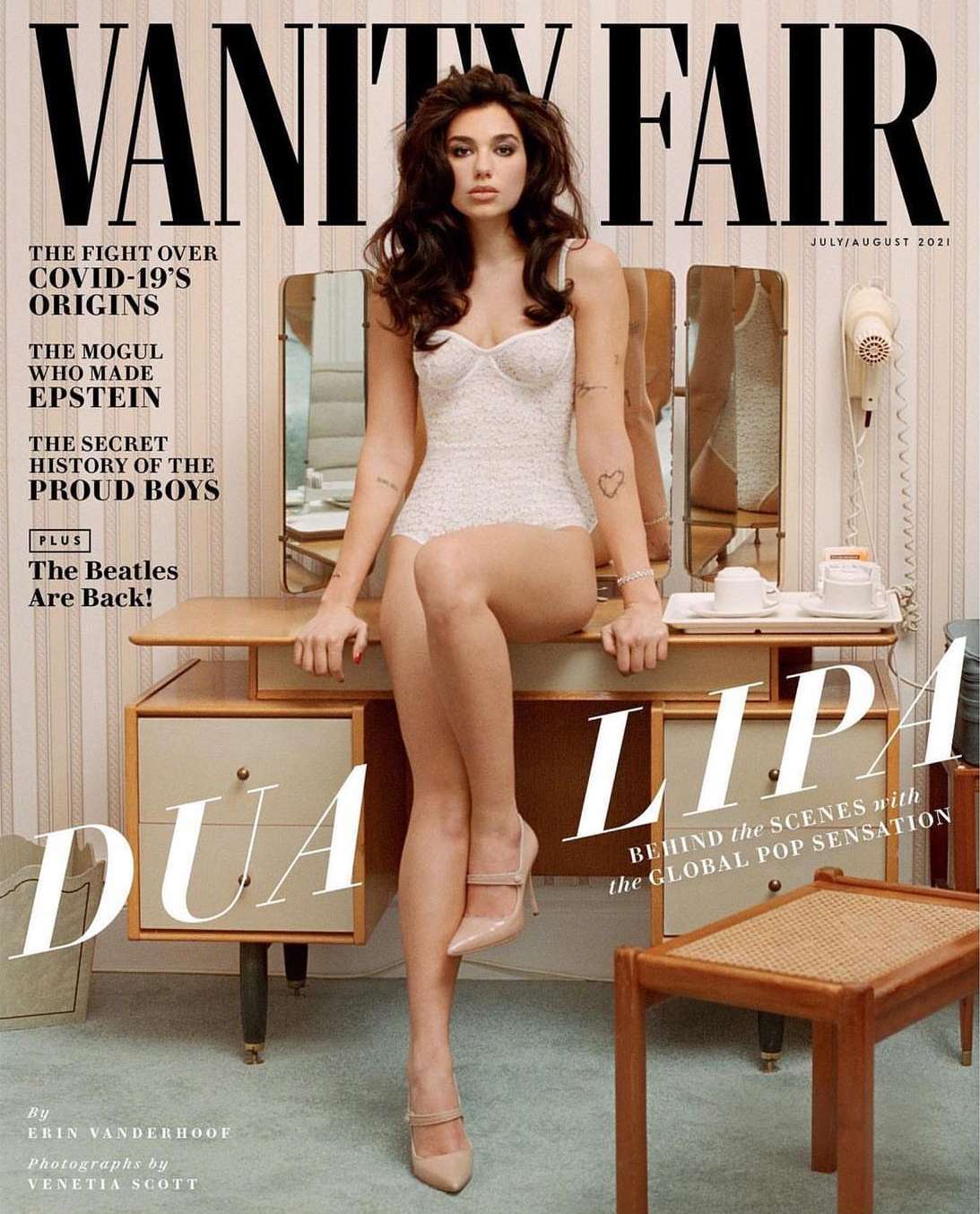 Magazine cover featuring Dua Lipa in a white bodysuit and heels, posed in front of a vintage vanity with a mirror. Vanity Fair masthead.