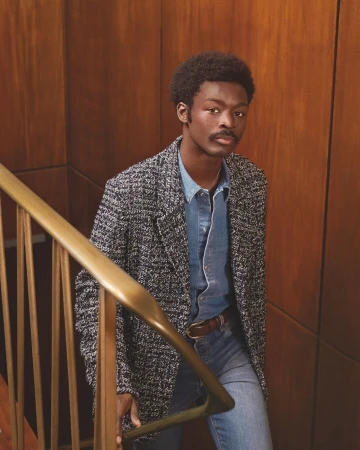 Black man in tweed blazer and denim shirt on staircase styled by Venetia Scott