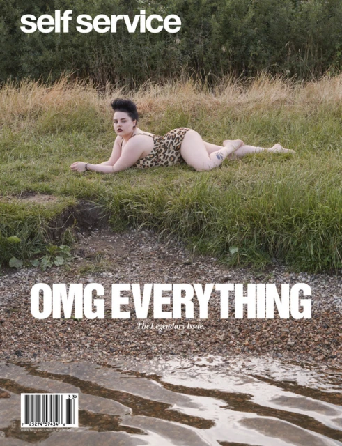 Magazine cover featuring a woman in a leopard print swimsuit lying on grass near a body of water, with the title 'self service'.