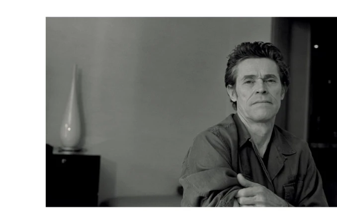 Black and white portrait of actor Willem Dafoe in an interior setting styled by Venetia Scott