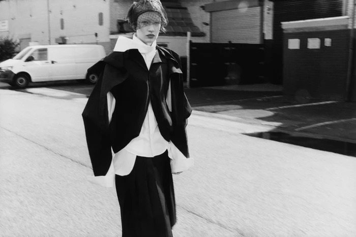 Model in black coat and veil walking on a street by photographer Gwenaelle Trannoy