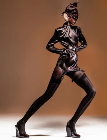 Model in satin top and stockings with a head wrap photographed by Cruz Valdez against a warm gradient background