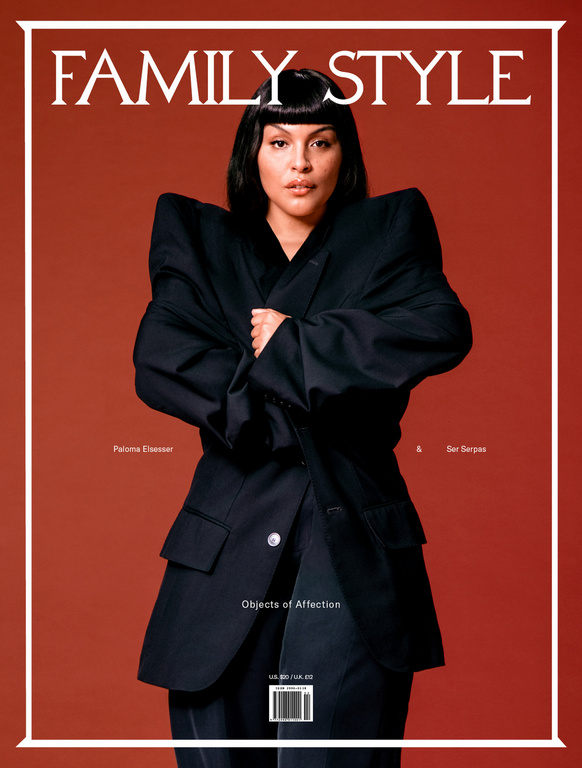 Model with dark bob haircut wearing an oversized black blazer against a warm reddish brown background
