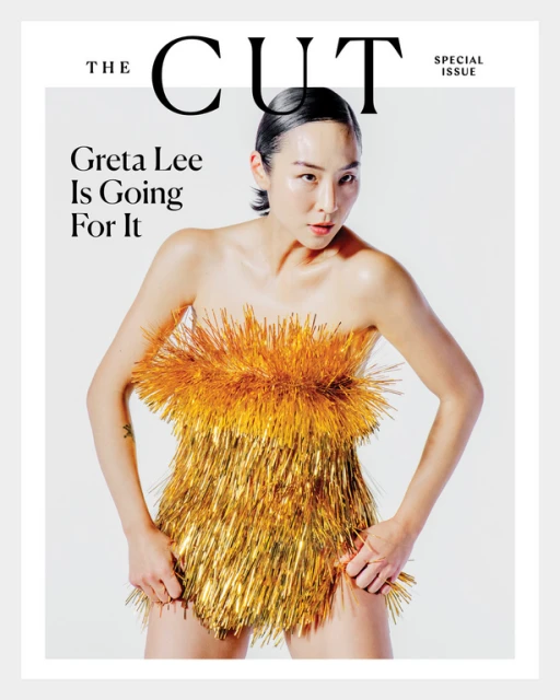 Magazine cover featuring Greta Lee wearing a gold fringed dress against a white backdrop, portrait orientation, stylish and eye-catching.