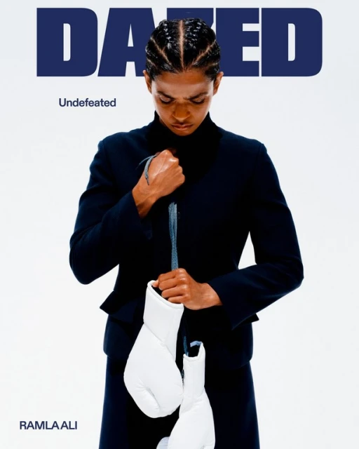 Ramla Ali on Dazed magazine cover wearing a black suit, holding white boxing gloves on a bright white background. 