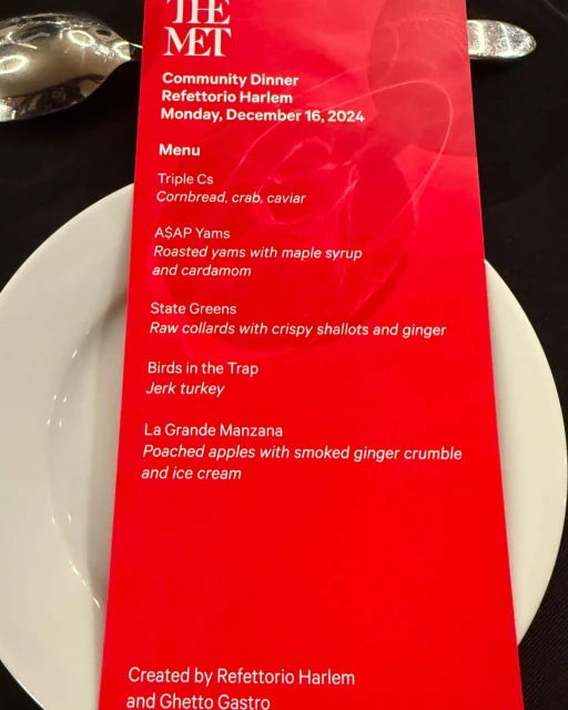 Close-up of a bright red menu card listing a multi-course dinner against dark background. Text includes names like Refettorio Harlem.