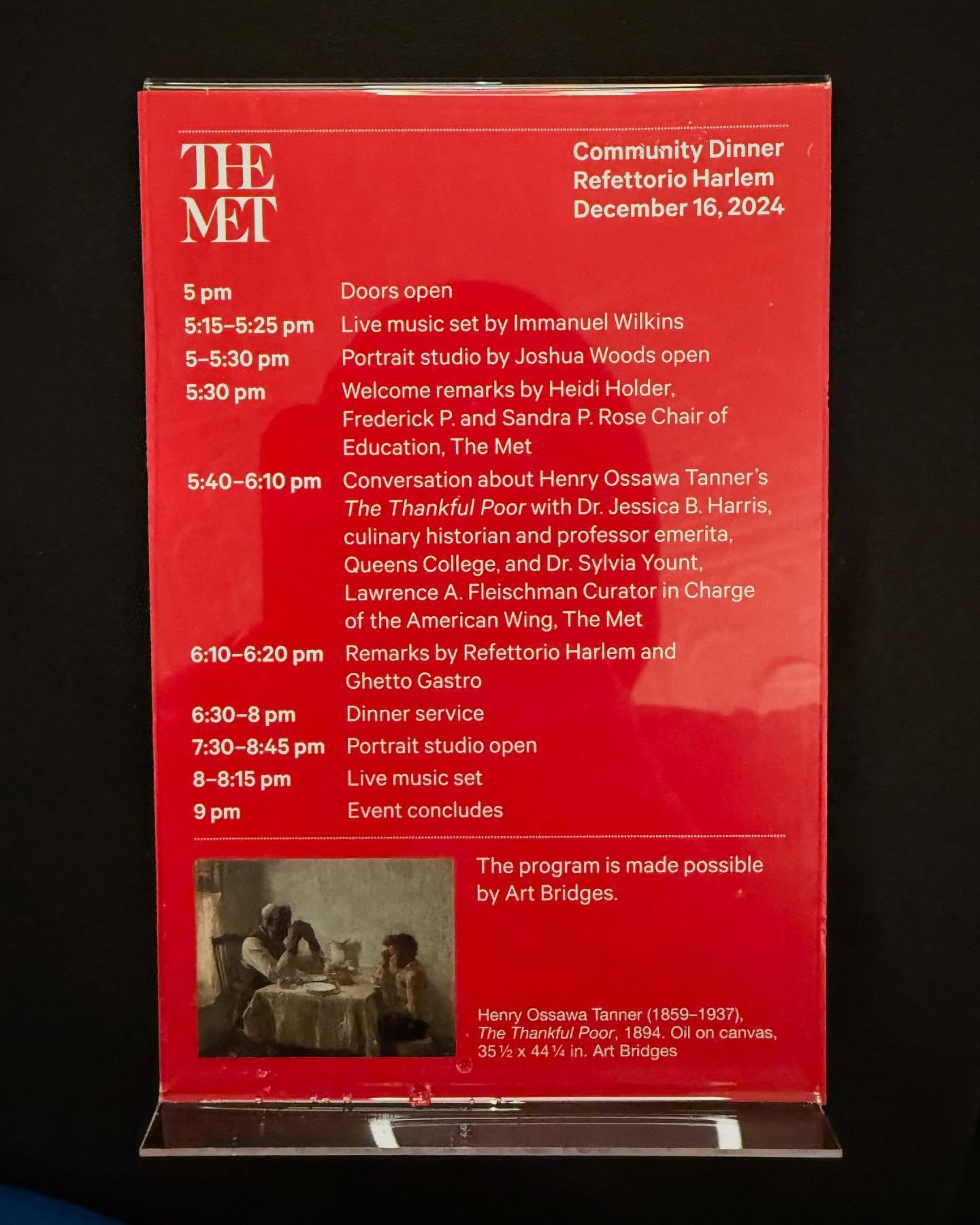 Red sign for Community Dinner Refettorio Harlem event, December 16, 2024, at The Met, featuring schedule and Henry Ossawa Tanner painting.