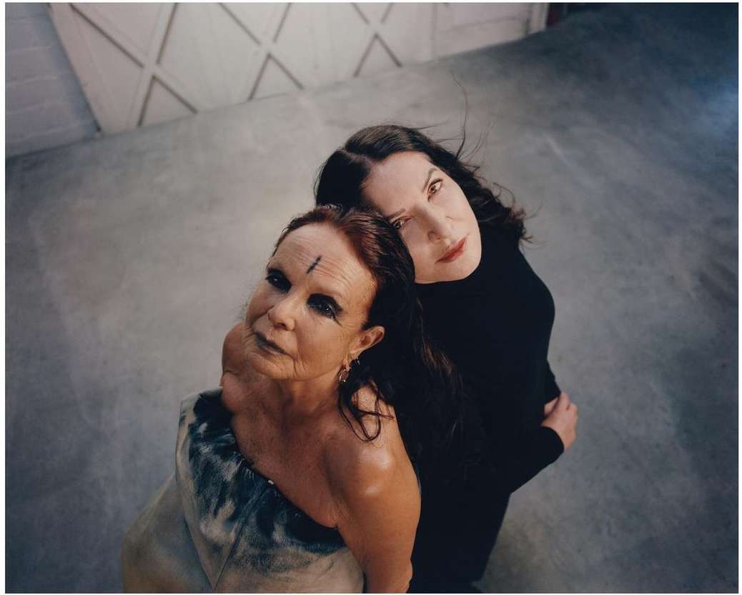 Two women posing closely back-to-back in an industrial concrete space photographed from above by Joshua Woods.