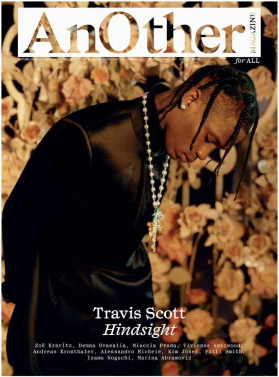 AnOther Magazine cover featuring Travis Scott. Close-up shot of the musician in a black satin-like jacket, flower arrangement background.