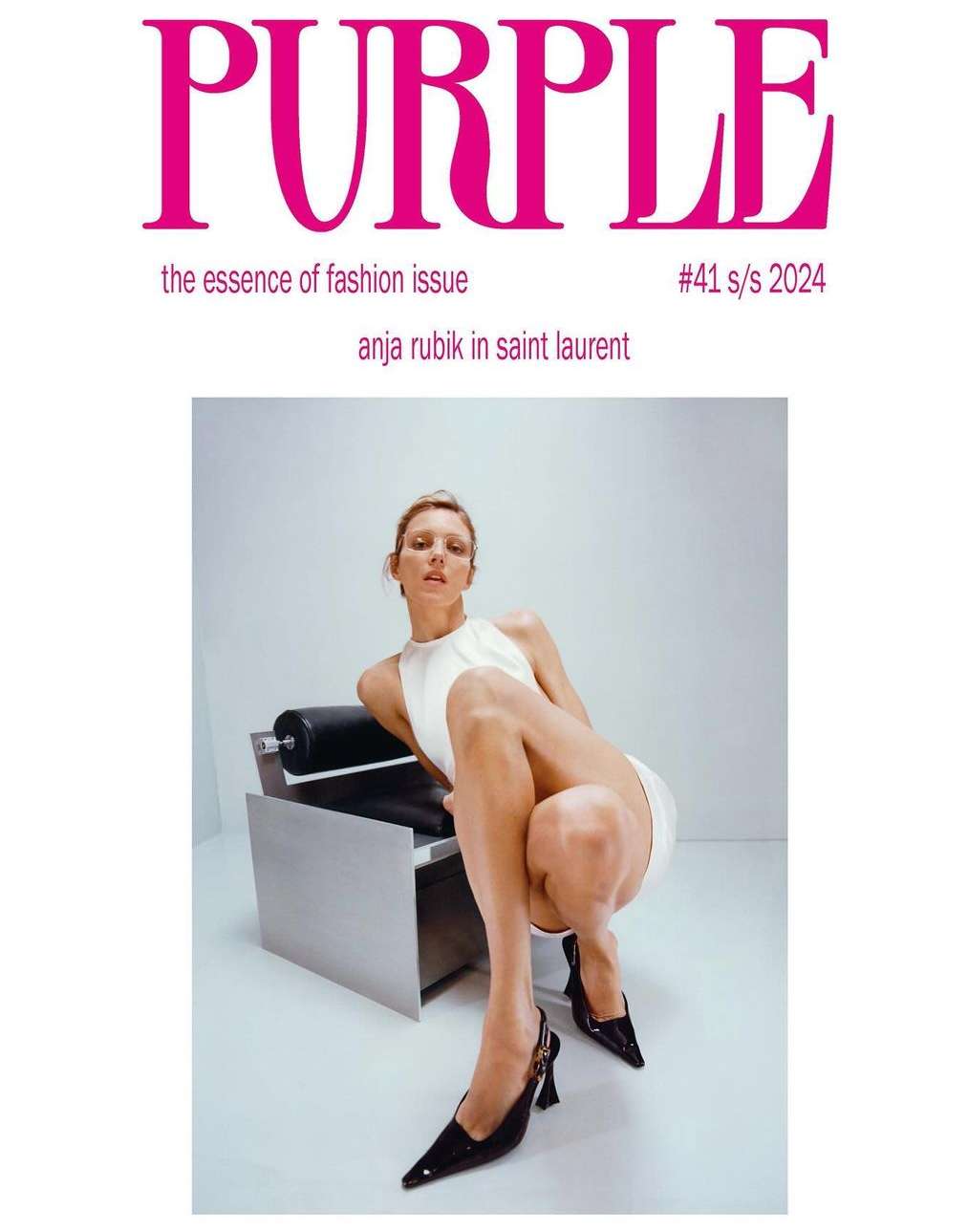 Fashion magazine cover featuring a blond woman in a white dress and black high heels sitting on a chair in a white photo studio.