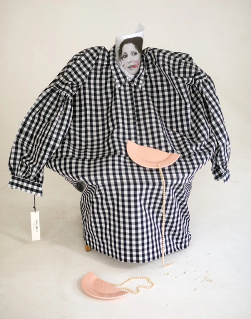 Stylized image with a black and white gingham shirt draped over a form, accessorized with pink plates and a pearl necklace.