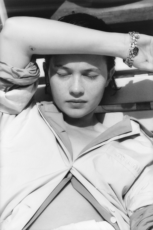 Close-up monochrome portrait of a woman with her arm raised across her forehead wearing a jeweled bracelet, styled by Helga Burrill.