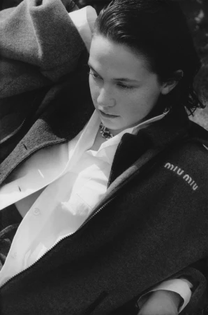 Portrait of a model wearing a dark coat over a white collared shirt styled by Helga Burrill