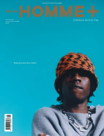 Magazine cover featuring a portrait of a black male model wearing an orange hat and silver chain against a turquoise background.