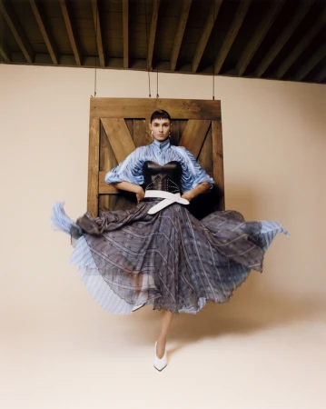 Model wearing a blue textured blouse and flared skirt with a black corset styled by Gabriella Karefa-johnson