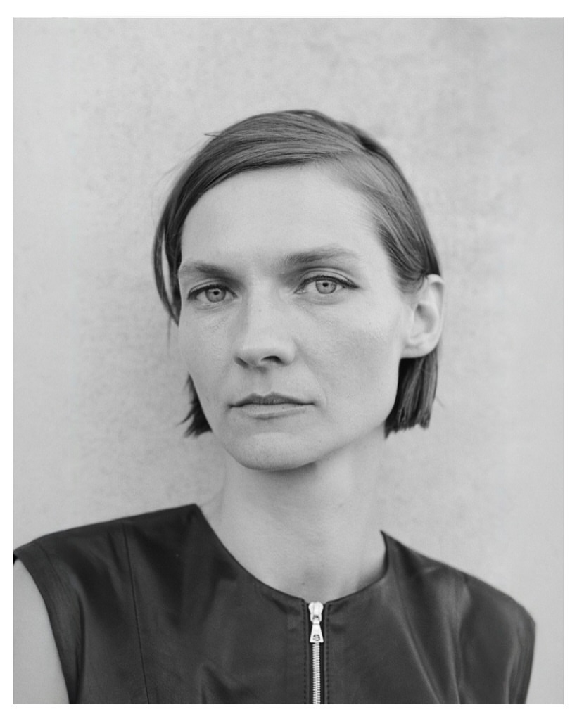 Monochrome portrait of a woman with short dark hair wearing a sleeveless dark top with a visible front zipper.