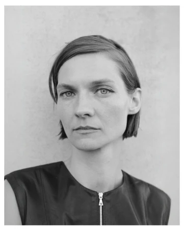 Monochrome portrait of a woman with short dark hair wearing a sleeveless dark top with a visible front zipper.