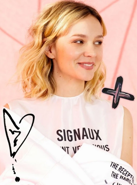 Portrait of a blonde woman wearing a white shirt with text, against a light pink background with illustrated design elements.
