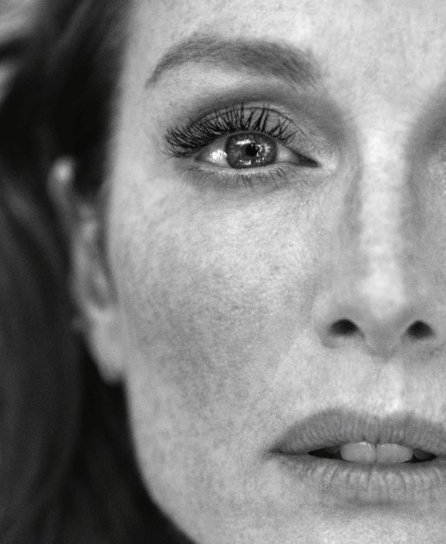 Close-up black and white portrait of a woman showing detailed freckles and textured eyelashes