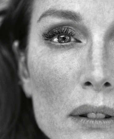 Close-up black and white portrait of a woman showing detailed freckles and textured eyelashes