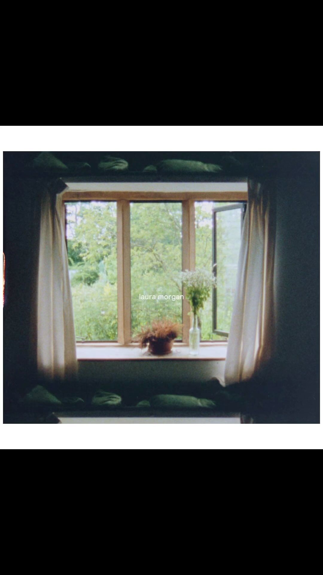 Indoor view of an open window with curtains and flowers, overlooking a lush green outdoor scene, creating a tranquil and inviting atmosphere.