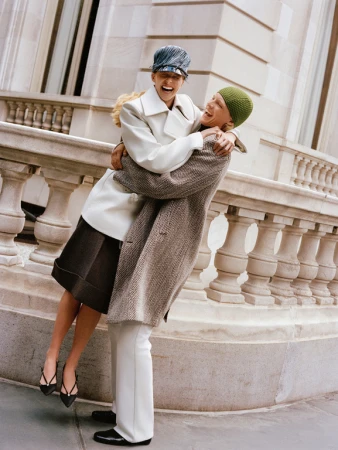 Two laughing models embracing on a classical stone balustrade, styled by Max Ortega